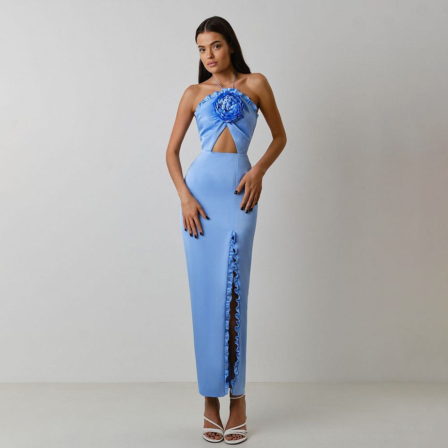 Light blue satin-like slit long dress with halter neckline, floral accent, keyhole cut-out, thigh-high slit with ruffles, and open-back design.