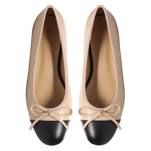 Beige and black ballet flats with a chic black cap toe and bow embellishment.